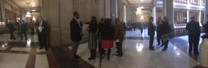 Wide angle of State House corridor outside House Chamber as (Center) Amos Interviews Legislators 