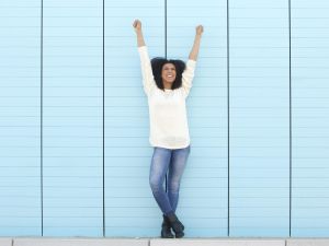 Full length portrait of a cheerful young woman smiling with hands in the air