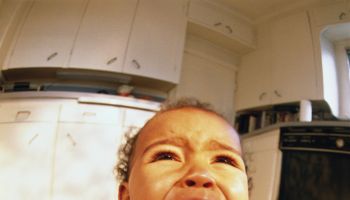 Baby boy (6-9 mo) sitting on kitchen floor, crying (wide angle)