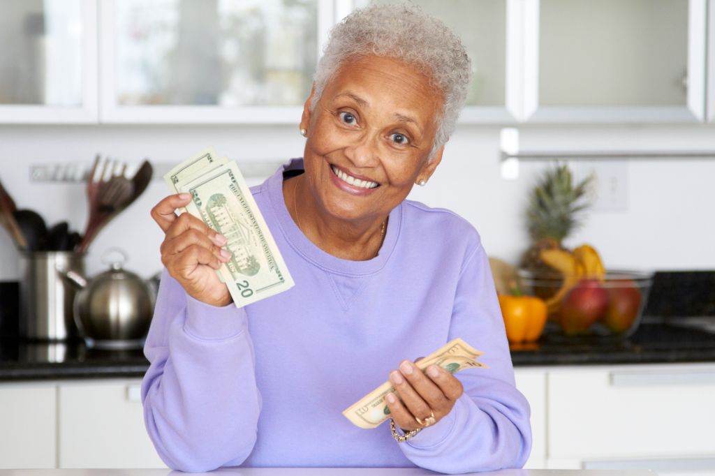 African American woman counting money in kitchen