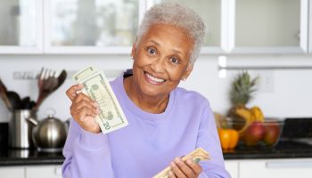 African American woman counting money in kitchen