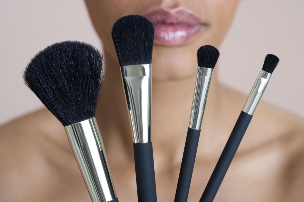 Woman holding four make-up brushes