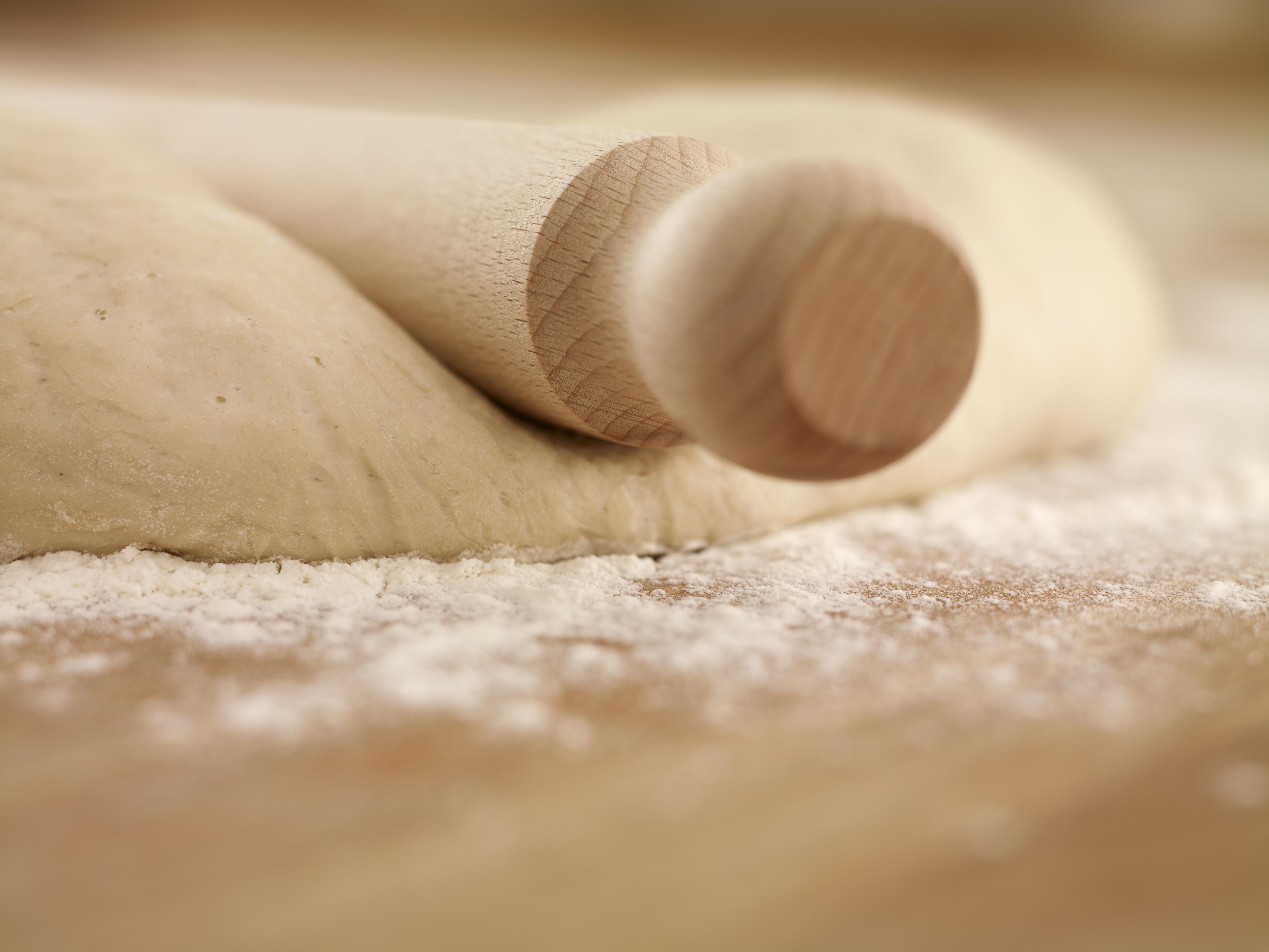 Close up of rolling pin on dough