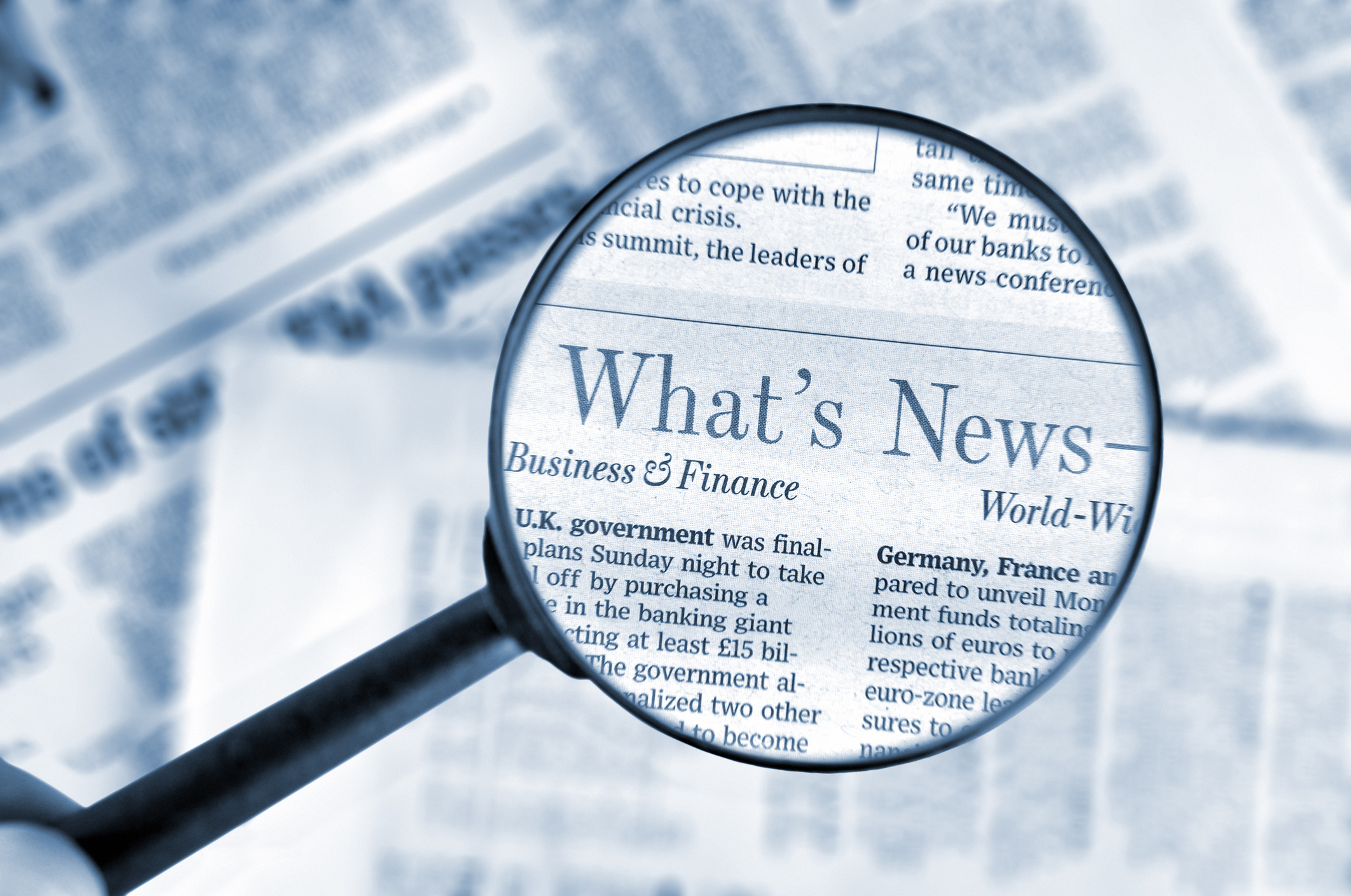 Close-up on magnifying glass above Wall Street Journal newspaper, blue