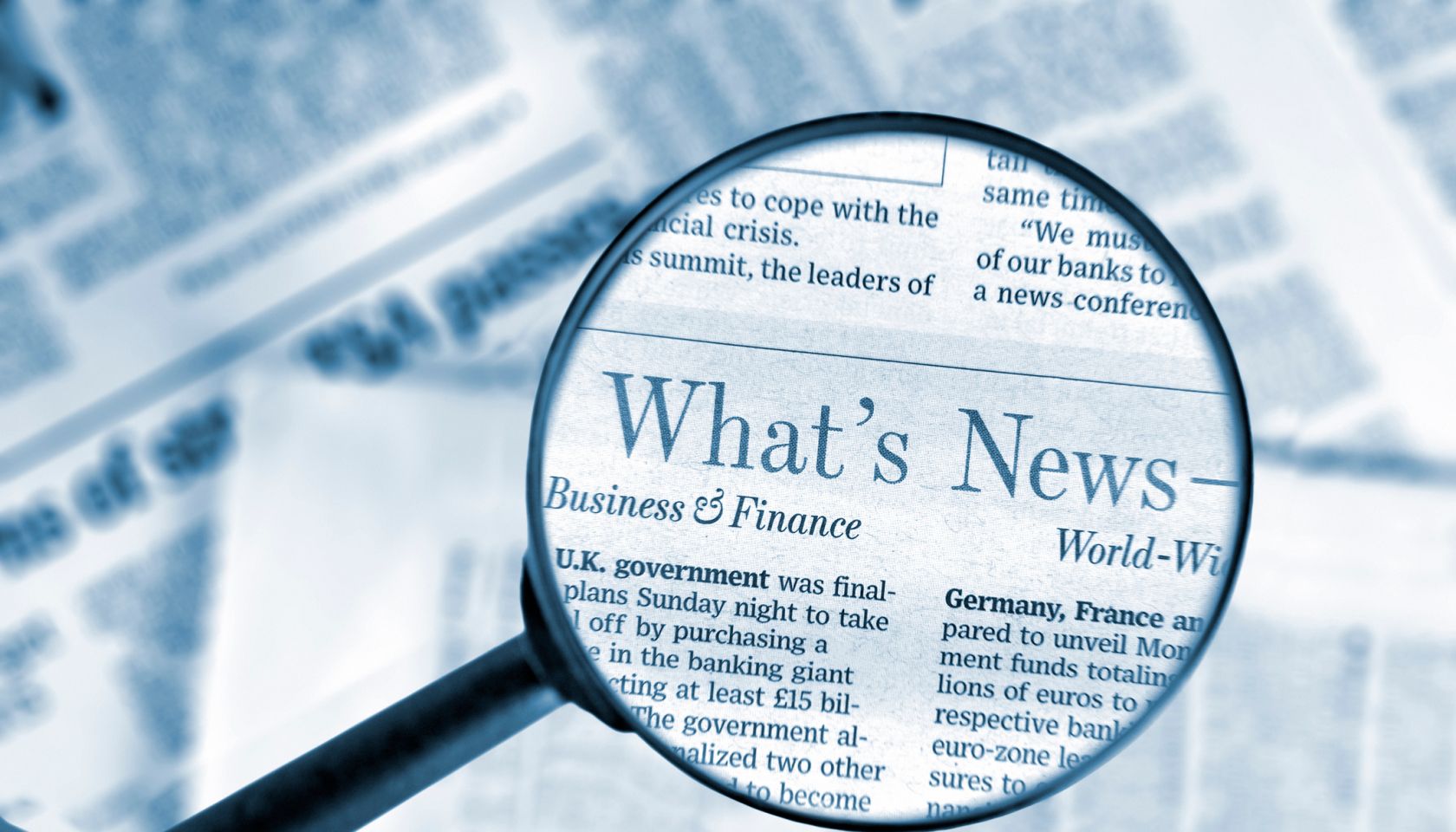 Close-up on magnifying glass above Wall Street Journal newspaper, blue