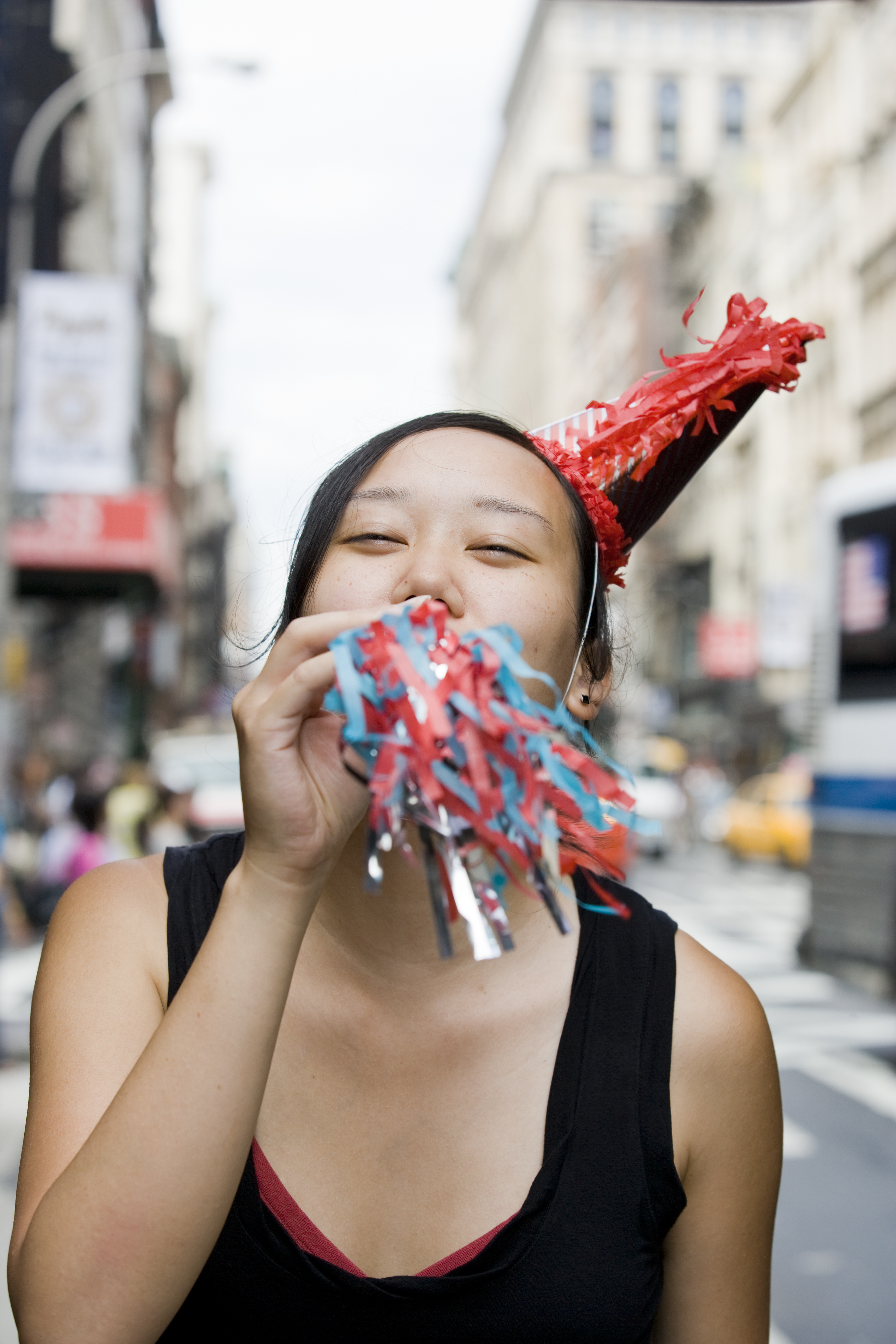 Young Korean woman blowing party horn in downtown city