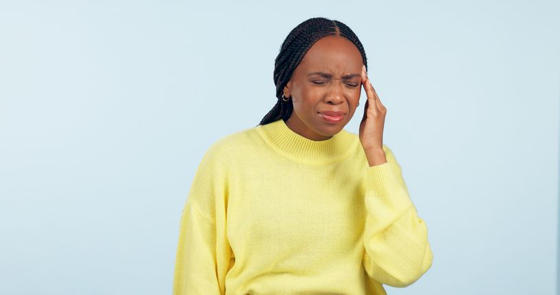 Woman, pain and headache in studio for stress, challenge and fatigue of mental health on blue background. African model massage temple for anxiety, brain fog or tired of migraine, vertigo and burnout