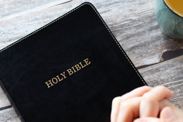Hands praying on top of Christian holy bible book