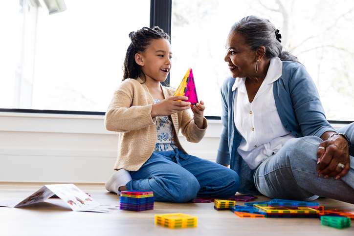 Grandmother and granddaughter playing with magnetic tiles together