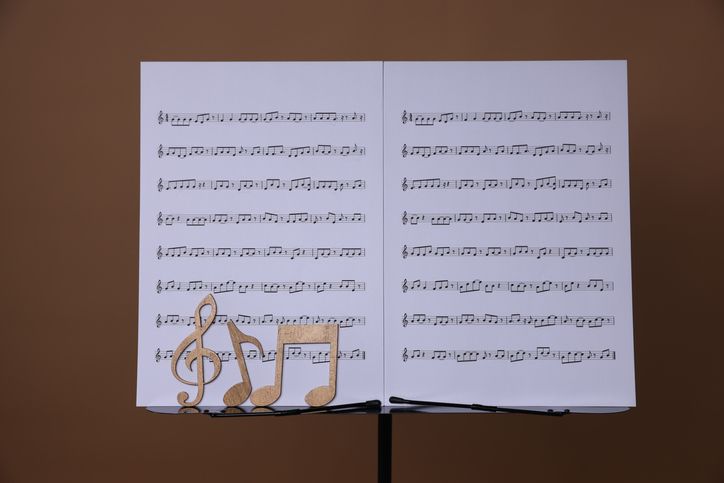 Stand with music sheets and wooden notes on dark beige background